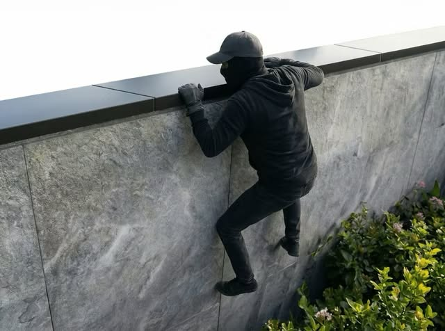 Intruder climbing over a perimeter wall, showing the climb-over attempt Apeiron Guard is designed to detect early